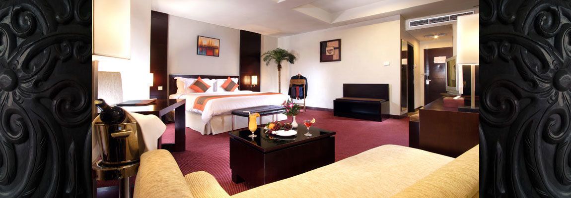 A hotel room with a bed, a desk, a television, and a coffee table.