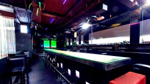 Un espace bar avec un long comptoir, des tabourets et un bloc de couleur rouge.