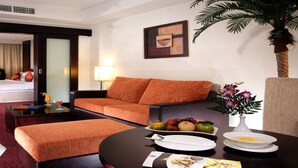 Une chambre d’hôtel comprenant un lit, un canapé, une table à manger avec des assiettes et un vase de fleurs, ainsi qu’une télévision.
