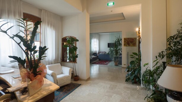 A spacious lobby with a seating area, a reception desk, and a large plant. - Hotel Santorotto (Sinalunga)