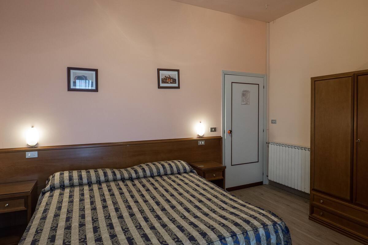 Ein Schlafzimmer mit Bett, Nachttischlampen, einem Kleiderschrank und einer Tür.