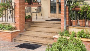 A hotel entrance with a sign reading "HOTEL SANTOROTTO," a door labeled "APERTO," and a small outdoor seating area with chairs. - Hotel Santorotto (Sinalunga)