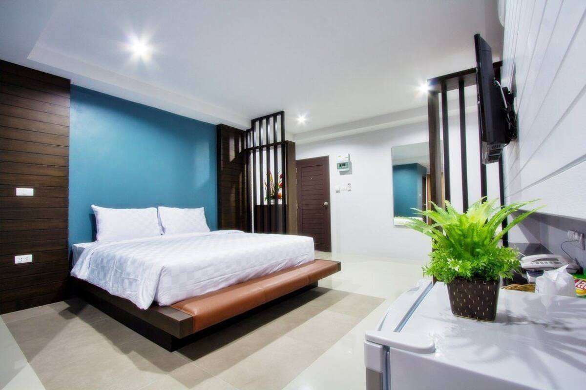 Ein modernes Hotelzimmer mit Bett, Fernseher, Pflanze und Badebereich.
