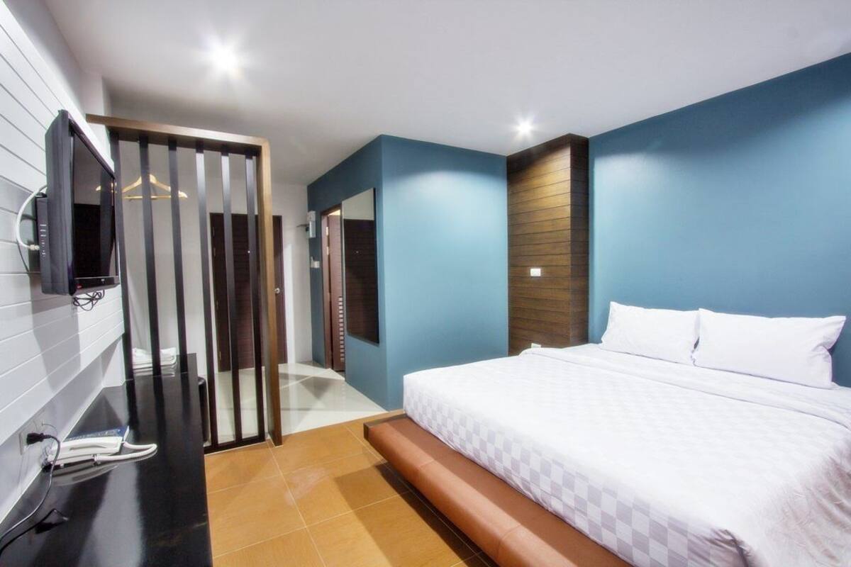 Ein Hotelzimmer mit Bett, Fernseher, Spiegel und einer Schiebetür.