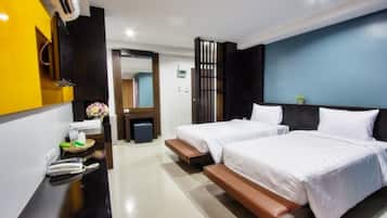 Une chambre d’hôtel avec deux lits, un bureau avec un téléphone et un panier, et un miroir.