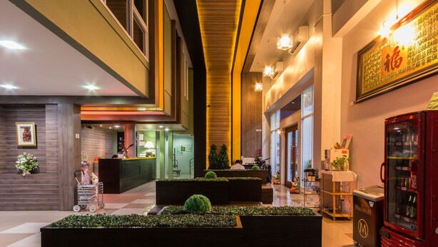 Um saguão de hotel com balcão de recepção, áreas de estar e uma máquina de refrigerantes Coca-Cola.