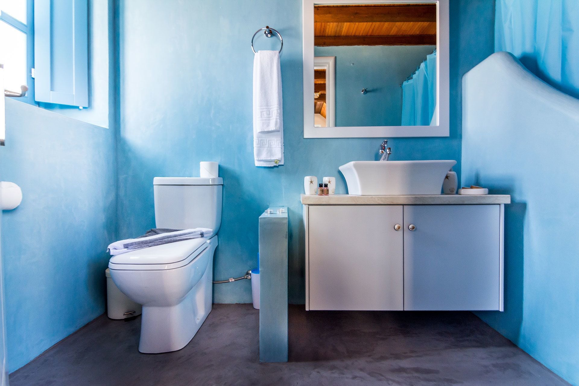 A bathroom with a toilet, sink, and mirror.
