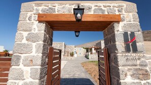 A stone archway leading to a courtyard with a wooden pergola overhead.