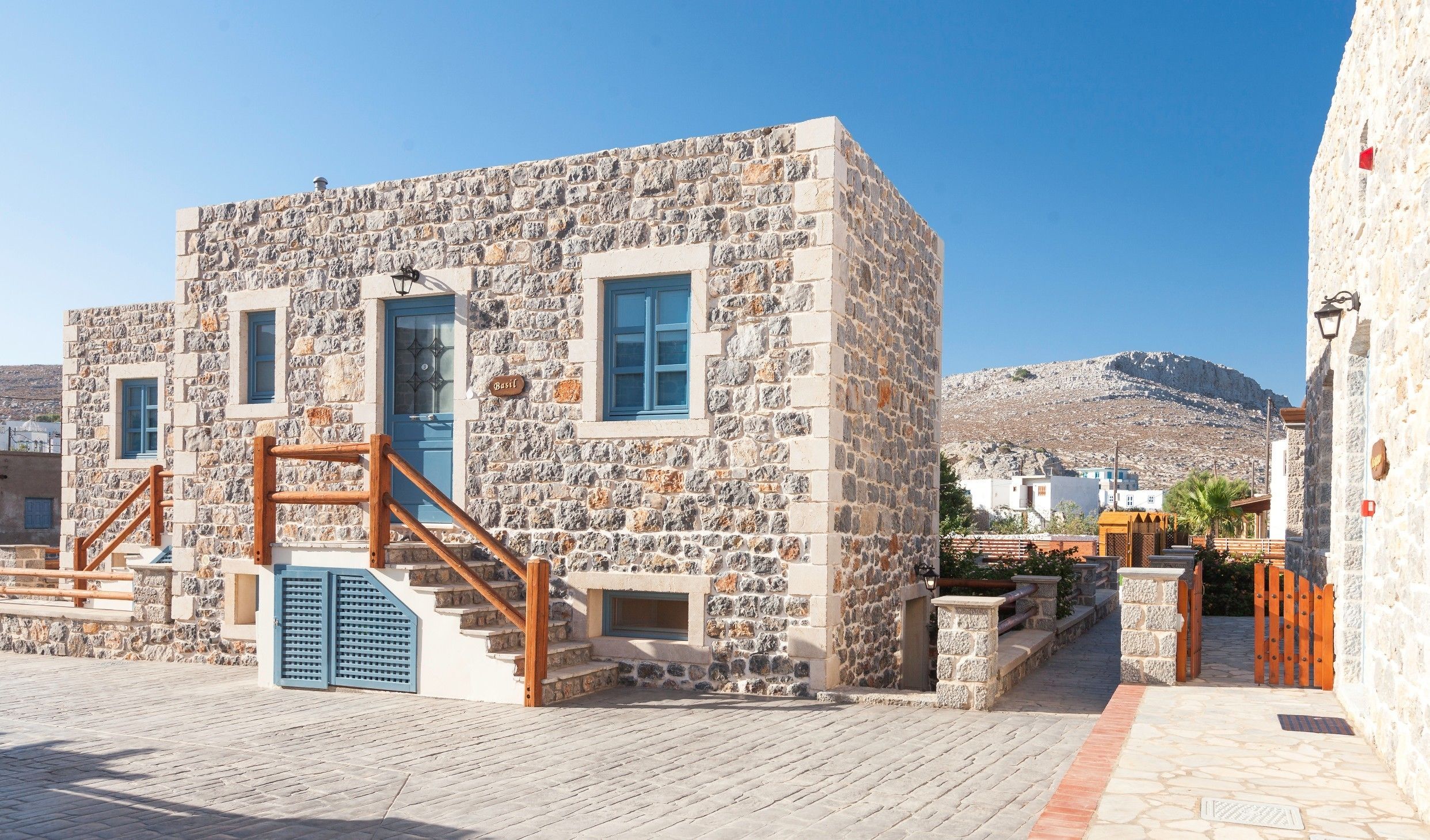 Un edificio de piedra con una escalera de madera y una puerta azul, con la leyenda 'Basil'.