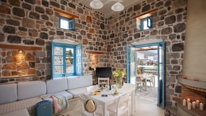 A stone-walled room with a sofa, a dining table, and a fireplace.