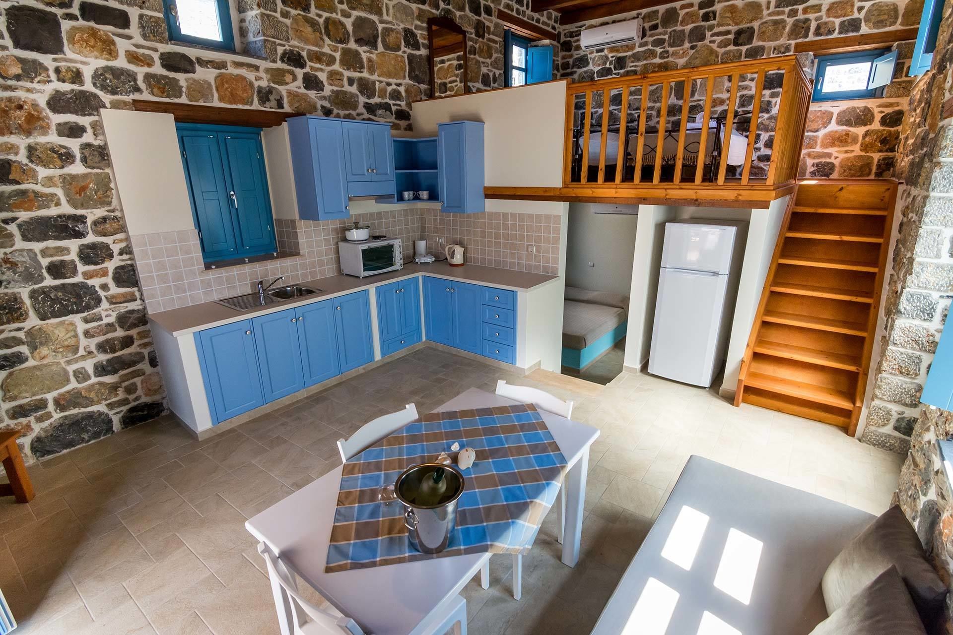 A kitchen with blue cabinets, a white refrigerator, and a dining area with a table and chairs.