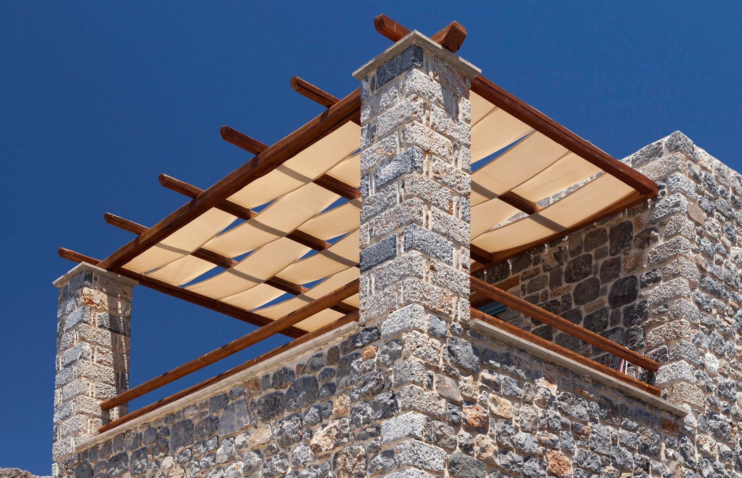 A stone building with a wooden pergola structure.