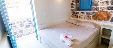 A bedroom with a stone wall, a blue door, and a bed with a towel and starfish decoration.