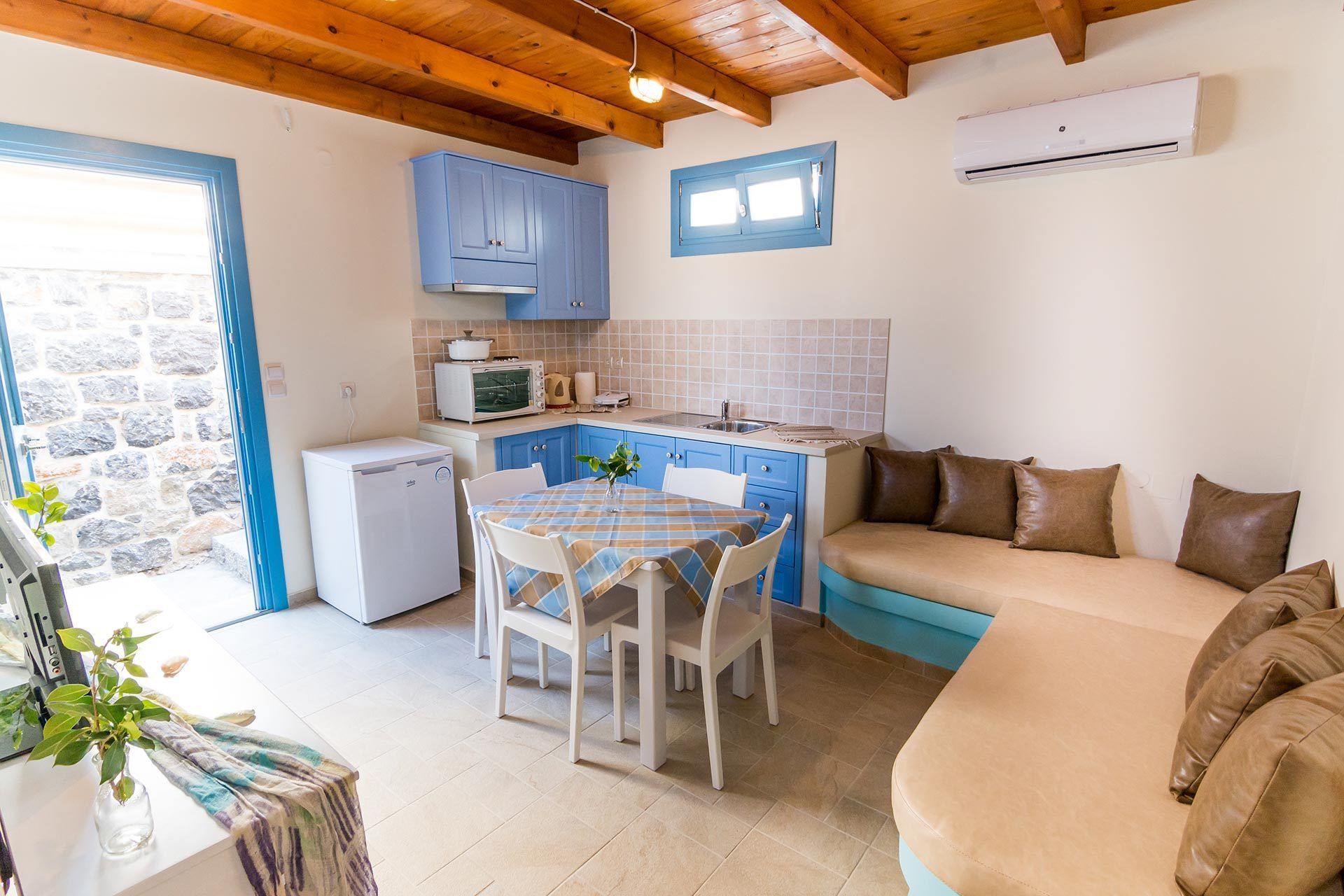 A compact kitchen with blue cabinets, a dining table, and a sofa.