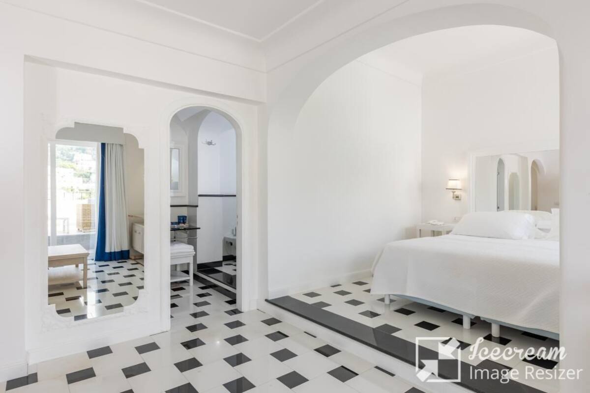 Habitación de hotel con cama, escritorio, silla y baño visible a través de un arco.