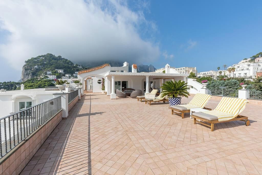 Terraza en la azotea con sillones de descanso, una planta en maceta y vistas a un paisaje montañoso.