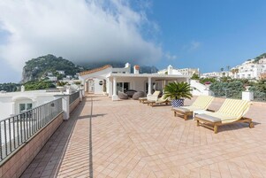 Terraza en la azotea con sillones de descanso, una planta en maceta y vistas a un paisaje montañoso.