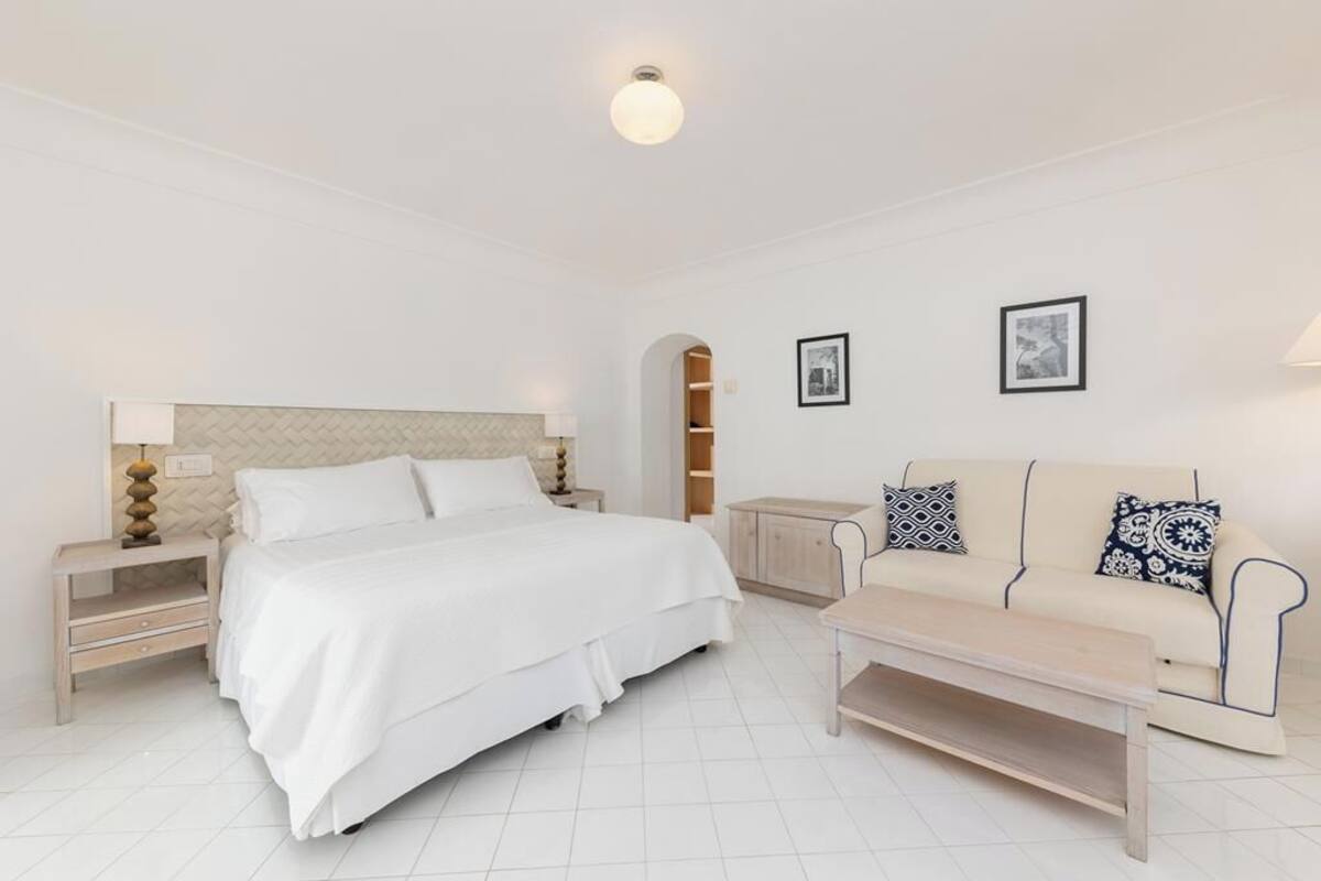 Un dormitorio con cama, mesitas de noche, un sofá y una mesa de centro.