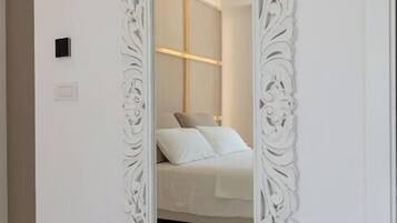 Un espejo grande y ornamentado con marco blanco sobre una pared blanca.