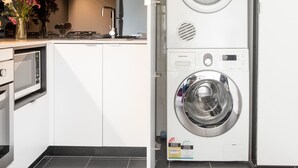 A compact kitchen with white cabinets, a built-in microwave, and a small countertop with a vase of flowers. - ABC Accommodation - 534 Flinders (Melbourne)