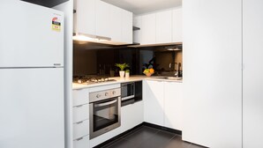 A modern kitchen with white cabinets, a built-in oven, a microwave, and a gas stove. - ABC Accommodation - 534 Flinders (Melbourne)