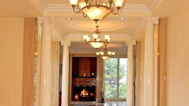 A grand hallway with a chandelier, columns, and a fireplace. - ABC Accommodation - Rosebud (Rosebud)