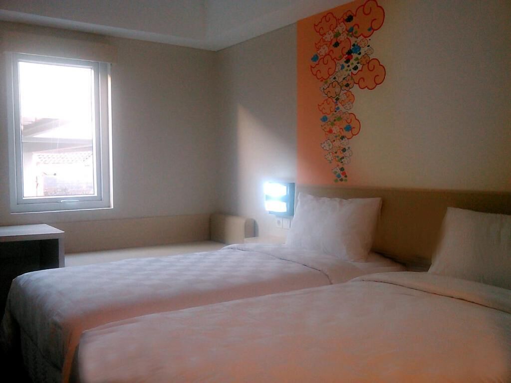 A hotel room with two beds, a window, and a wall decoration.