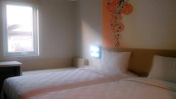 A hotel room with two beds, a window, and a wall decoration.