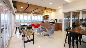 A modern lounge area with a foosball table, seating, and a reception desk.