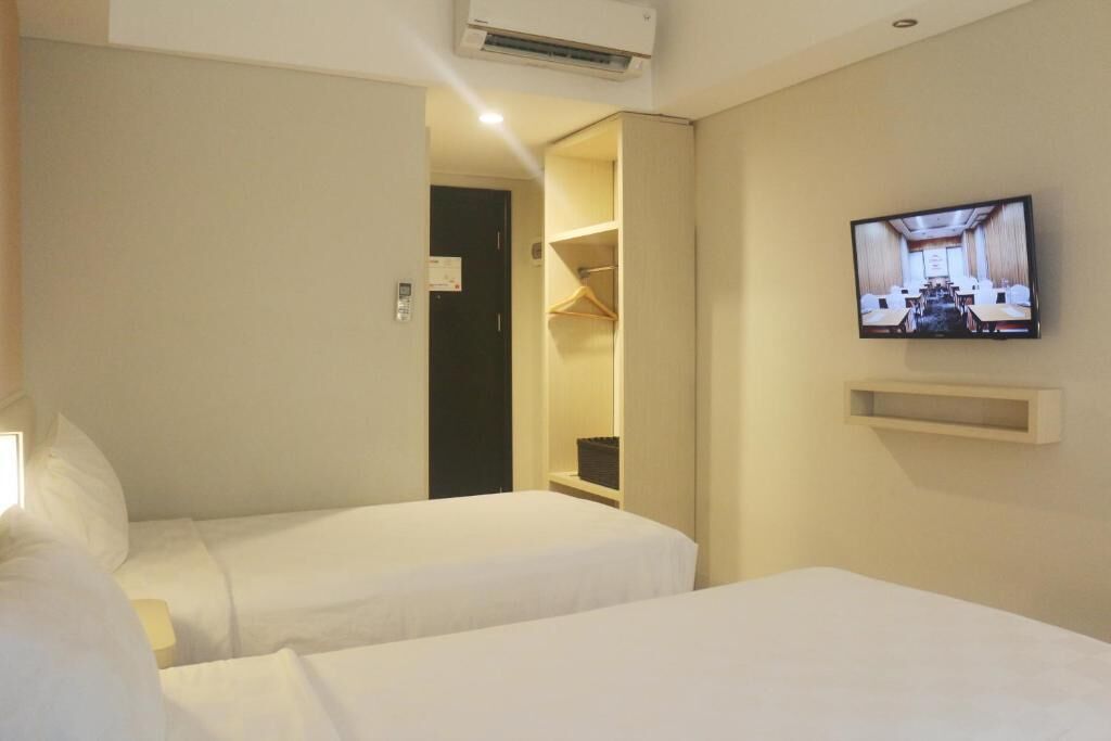 A hotel room with two beds, a TV mounted on the wall, and a walk-in closet.