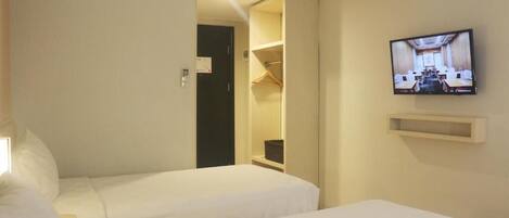 A hotel room with two beds, a TV mounted on the wall, and a walk-in closet.
