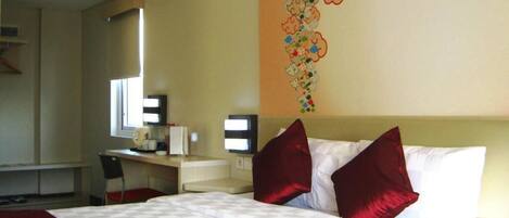 A hotel room with a bed, a desk, and a chair.