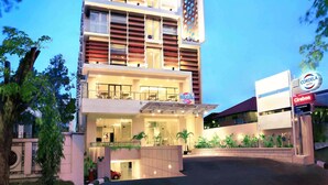 A hotel with a modern design, featuring multiple floors, a prominent entrance, and a well-lit facade.