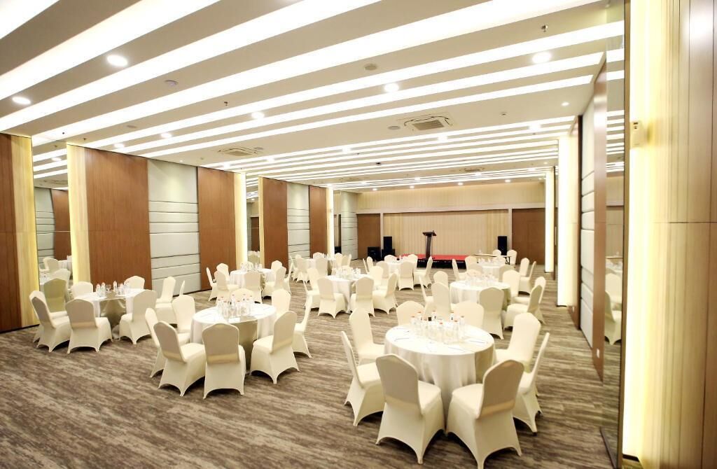 A large banquet hall with round tables and white chairs, equipped with tableside settings.