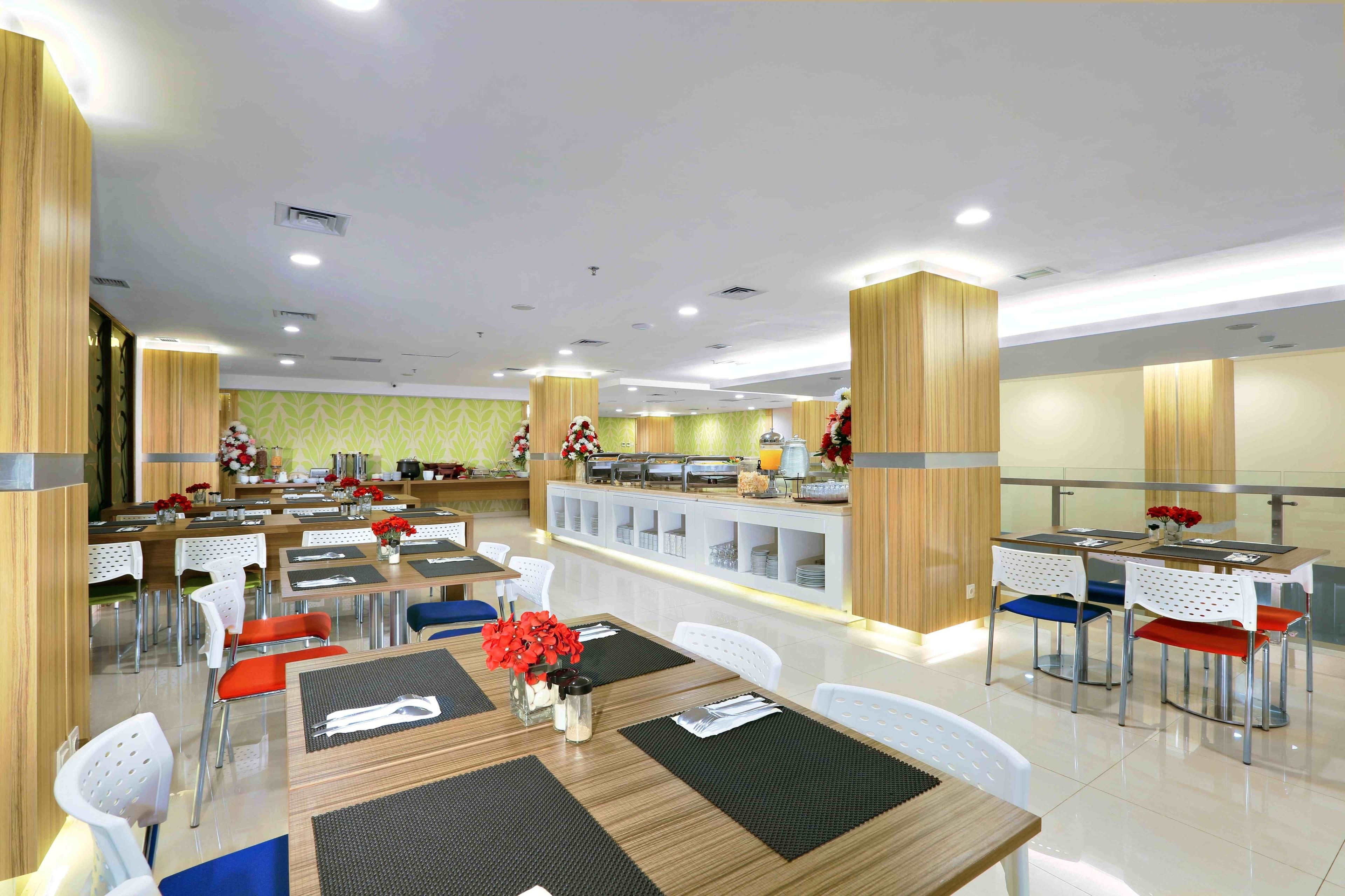 A modern dining area with multiple tables and chairs, a buffet counter, and a decorative wall with flowers.