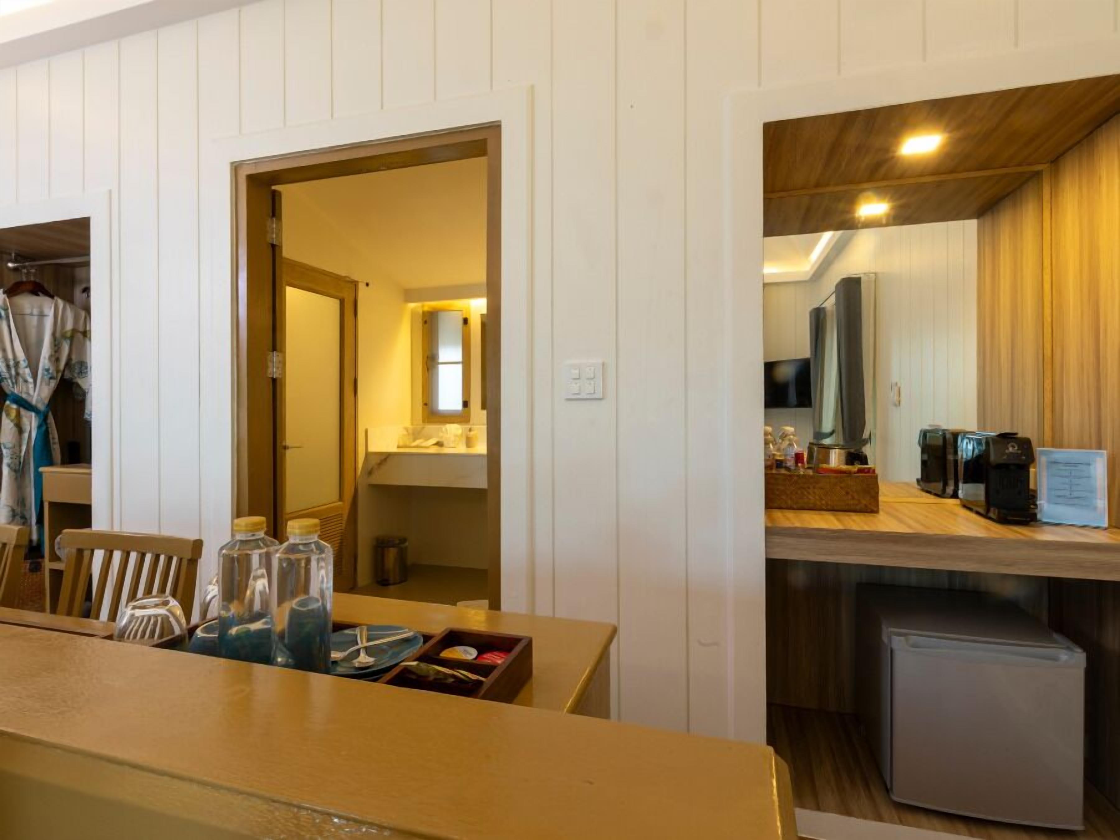 Une chambre d’hôtel compacte dotée d’une kitchenette, d’un coin repas avec une table dressée pour deux personnes et d’un petit réfrigérateur.