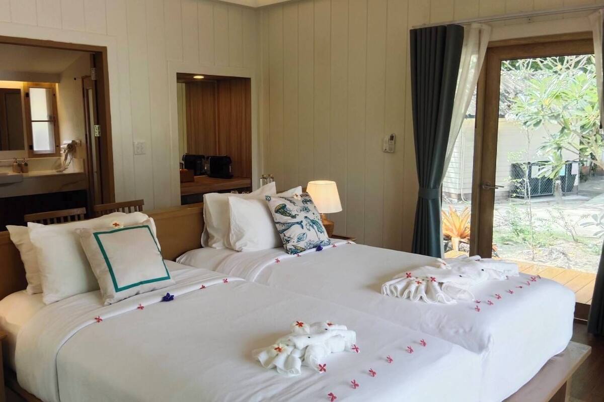 Hotelkamer met twee bedden, een zithoek, een groot raam met gordijnen en uitzicht op de omgeving.