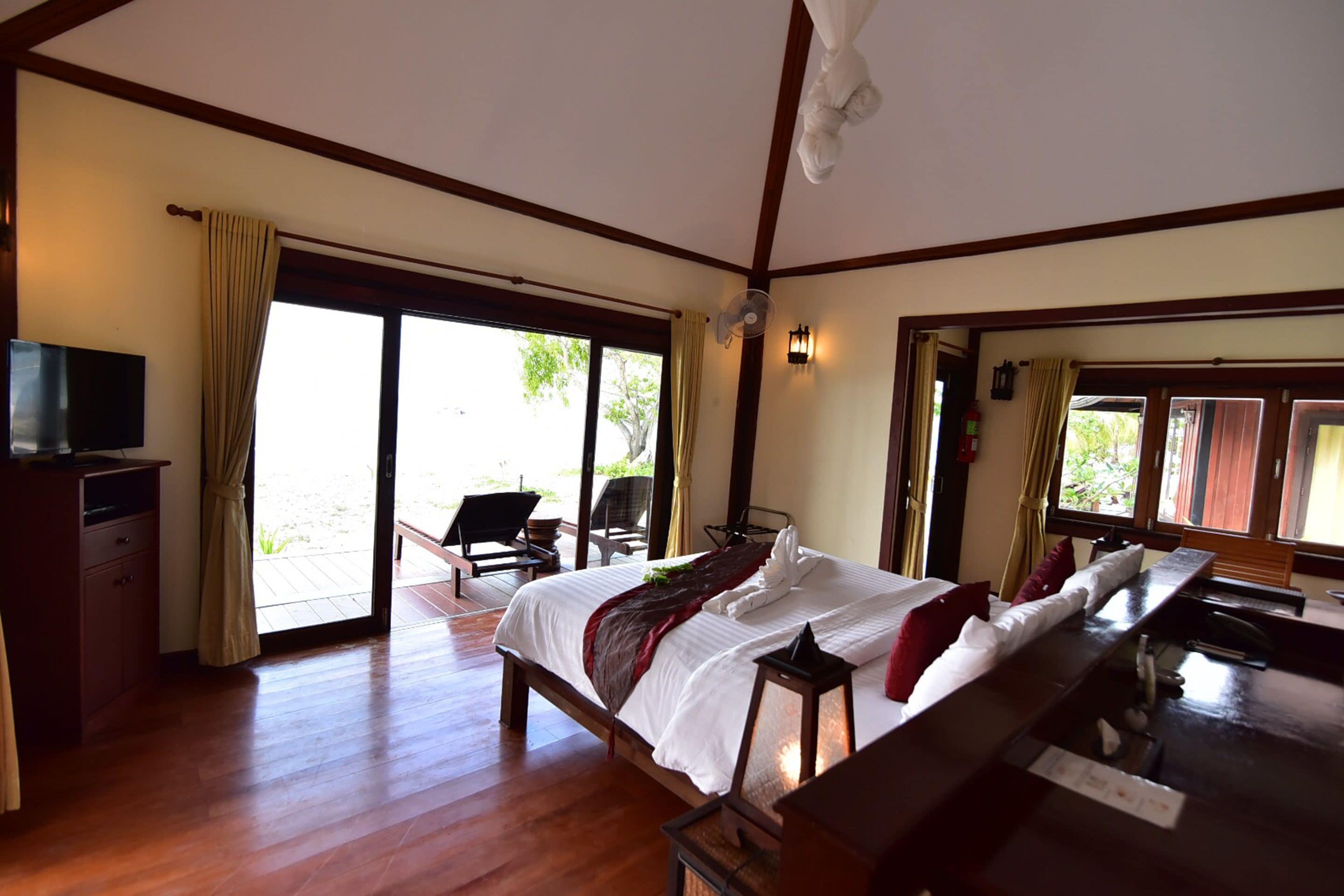 A hotel room with a bed, a desk, a TV, and a view of the outdoors.