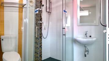 Un baño con inodoro, ducha con mampara de vidrio y lavabo.