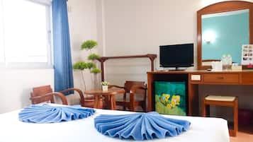 Ein Hotelzimmer mit einem Bett, einem Schreibtisch mit Computer, einem Fernseher und einem kleinen Tisch mit Stühlen.