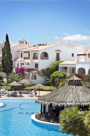 Una piscina al aire libre, sombrillas, sillones reclinables de piscina