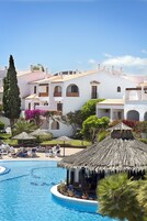 Una piscina al aire libre, sombrillas, sillones reclinables de piscina