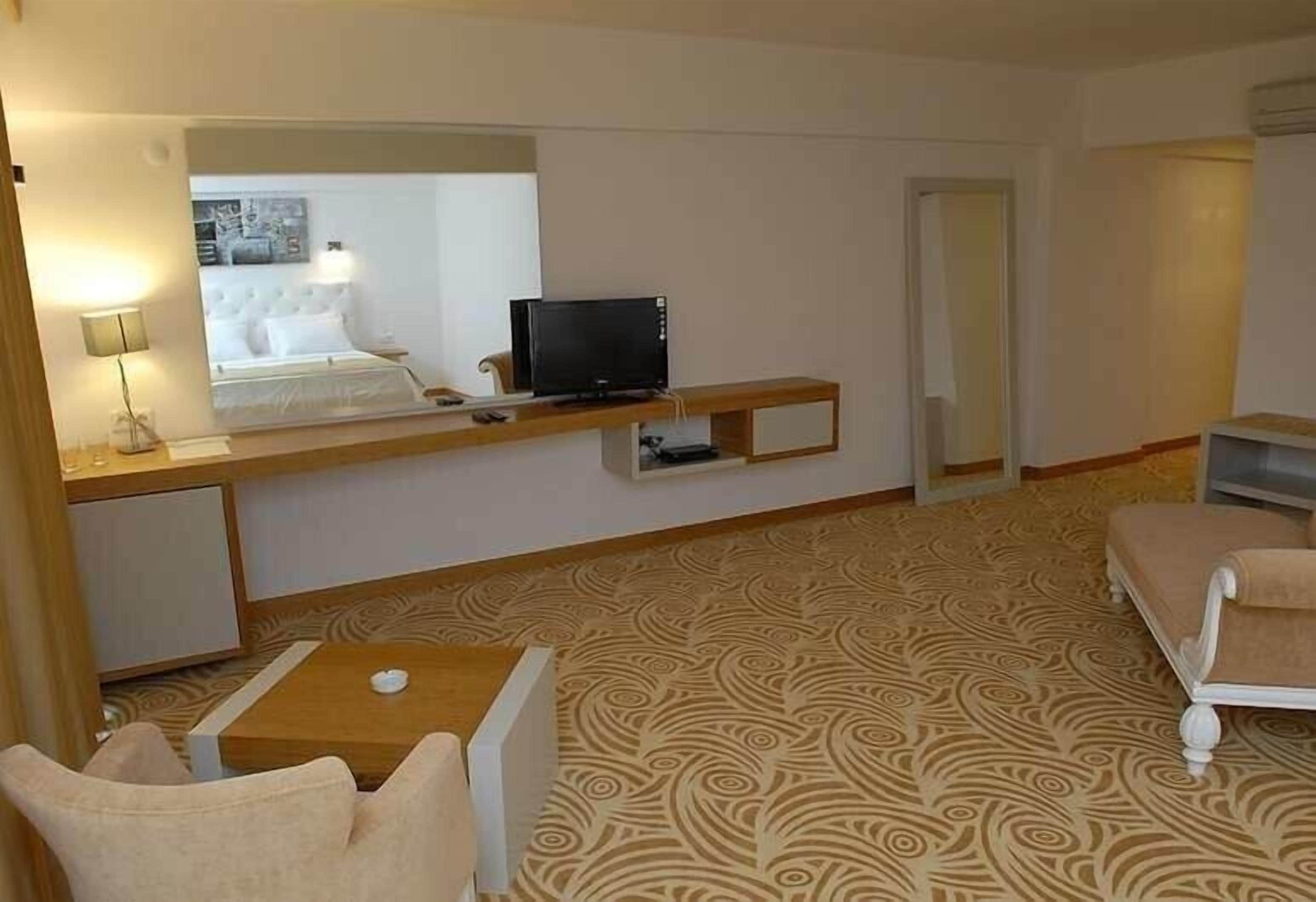 Een hotelkamer met een bed, een bureau met een computer, een klein tafeltje en een stoel.