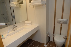 Ein Badezimmer mit weißem Waschbecken, einem Spiegel, einer Toilette und einer Duschkabine.