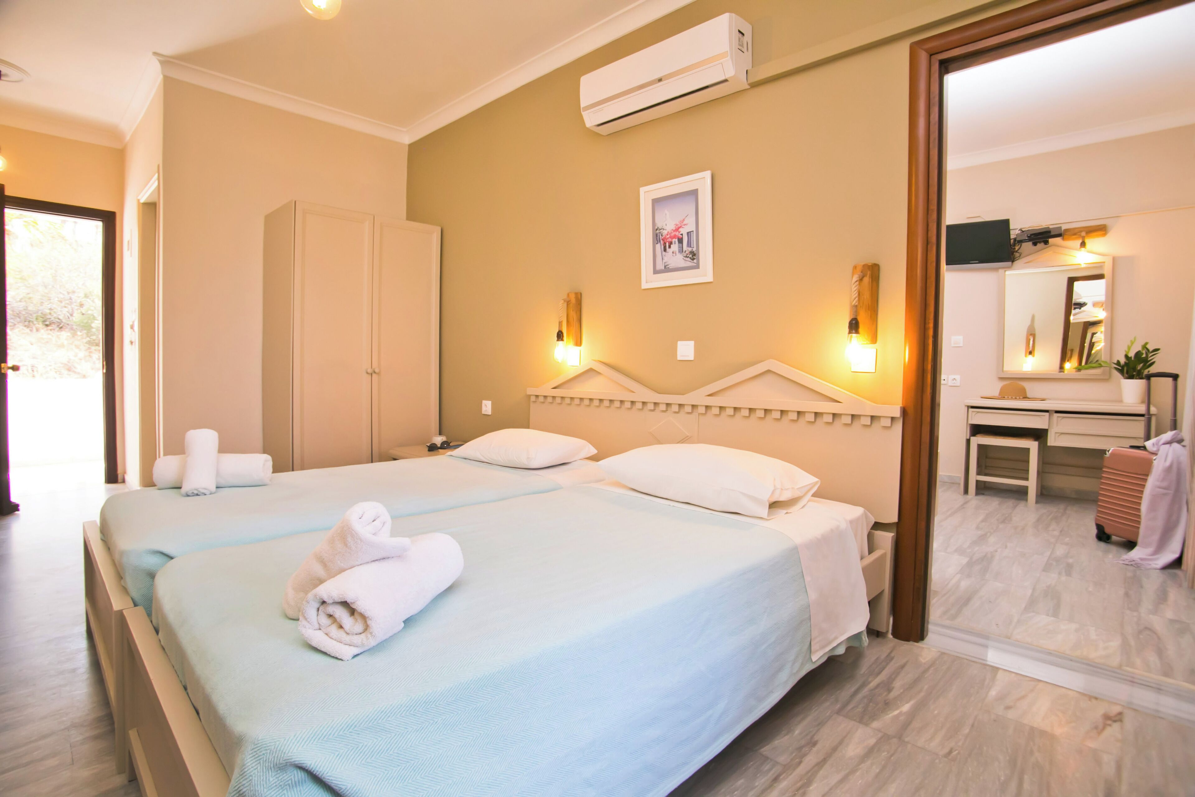 Une chambre d’hôtel avec deux lits, un bureau, un miroir et un appareil de climatisation.
