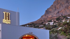 Un hotel con un llamativo letrero iluminado, diseño arquitectónico moderno y vistas a un paisaje montañoso al fondo.