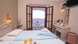 Habitación de hotel con cama, bandeja de desayuno, balcón abierto y escritorio con espejo.