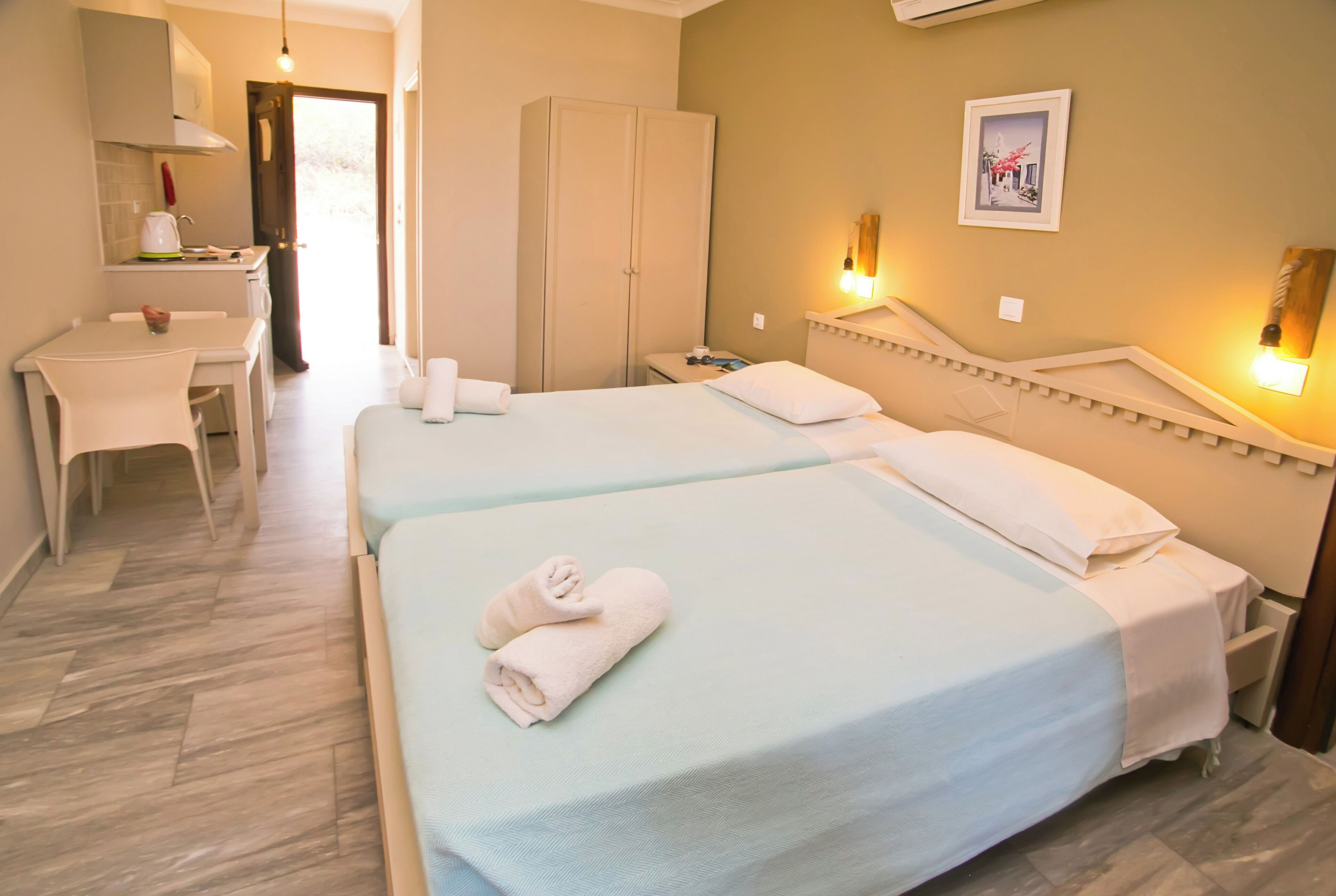 Habitación de hotel con dos camas, un escritorio pequeño y un armario.