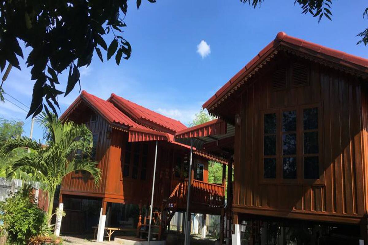 A traditional wooden building with a red roof, large windows, and a balcony.