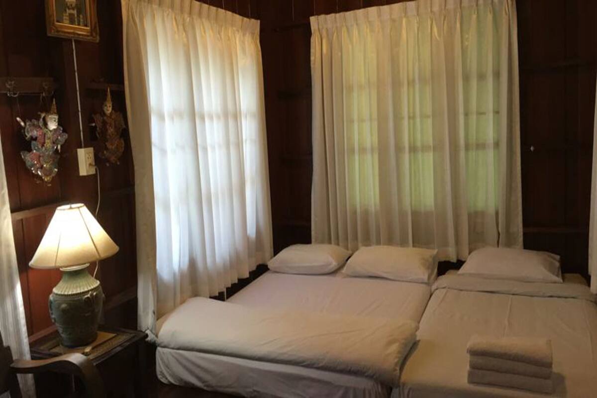 A room with a bed, a nightstand with a lamp, and curtains.